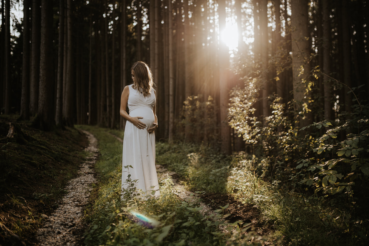 Schwangere Frau mit weißem Kleid im Wald bei Sonnenuntergang als Teil von Paarfotos in Grieskirchen, fotografiert von Kosia
