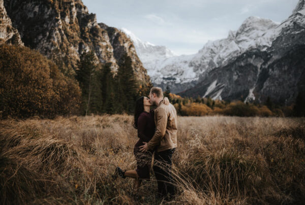 Pärchen das sich küsst, bei einem Babybauchshooting am Almsee mit Bergpanorama im Hintergrund, fotografiert von Paarfotograf Kosia