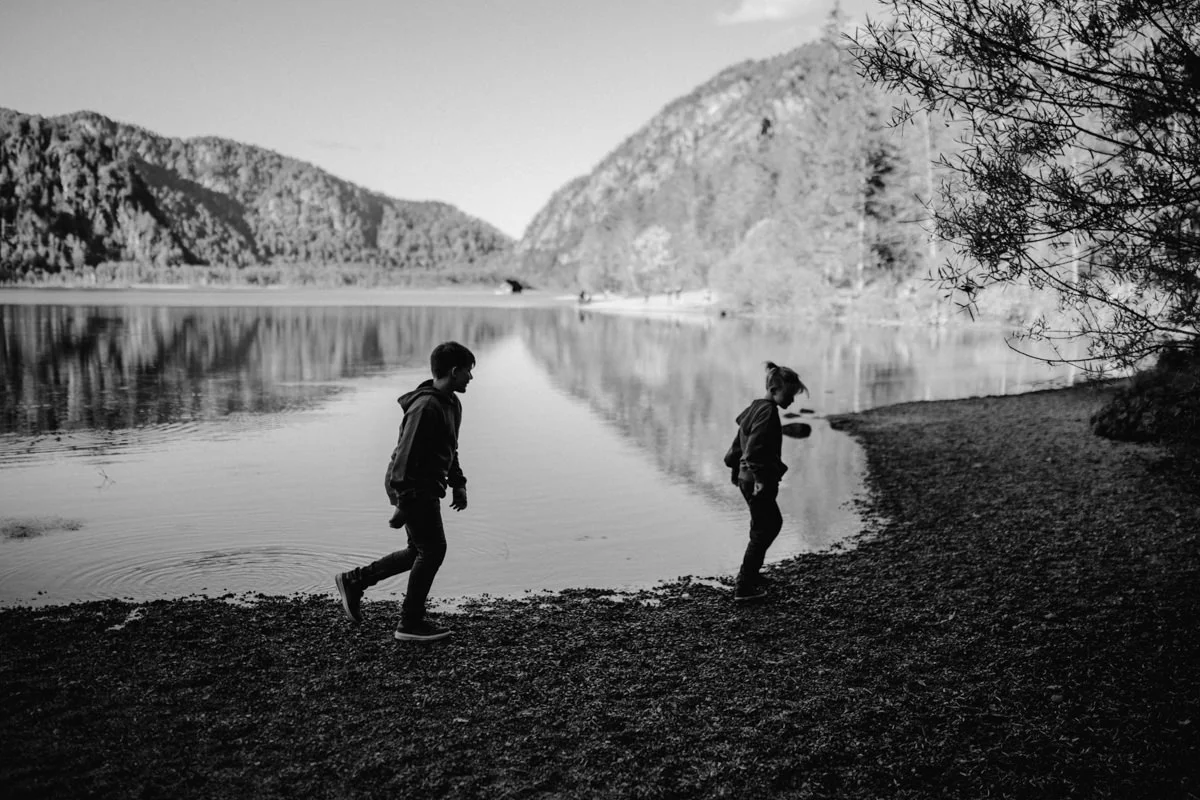 Schwarz-Weiß Foto von zwei Jungen, die am Almsee Ufer entlang laufen, fotografiert von Familienfotograf Kosia