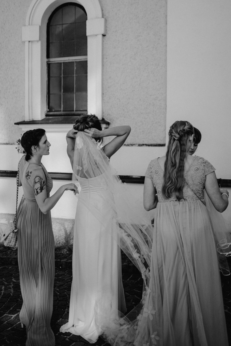 Braut richtet ihren Brautschleier vor der kirchlichen Hochzeit in Ebensee, von Fotograf Kosia