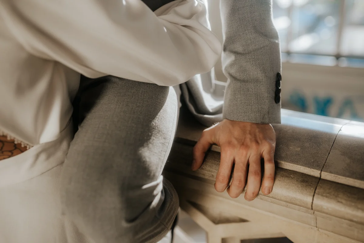 Detailfoto der Hand des Bräutigams, der einen grauen Anzug trägt und sich beim Geländer im Medienkulturhaus in Wels abstützt. Fotografiert bei einem Hochzeit-Shooting in Wels, von Hochzeitsfotograf Kosia