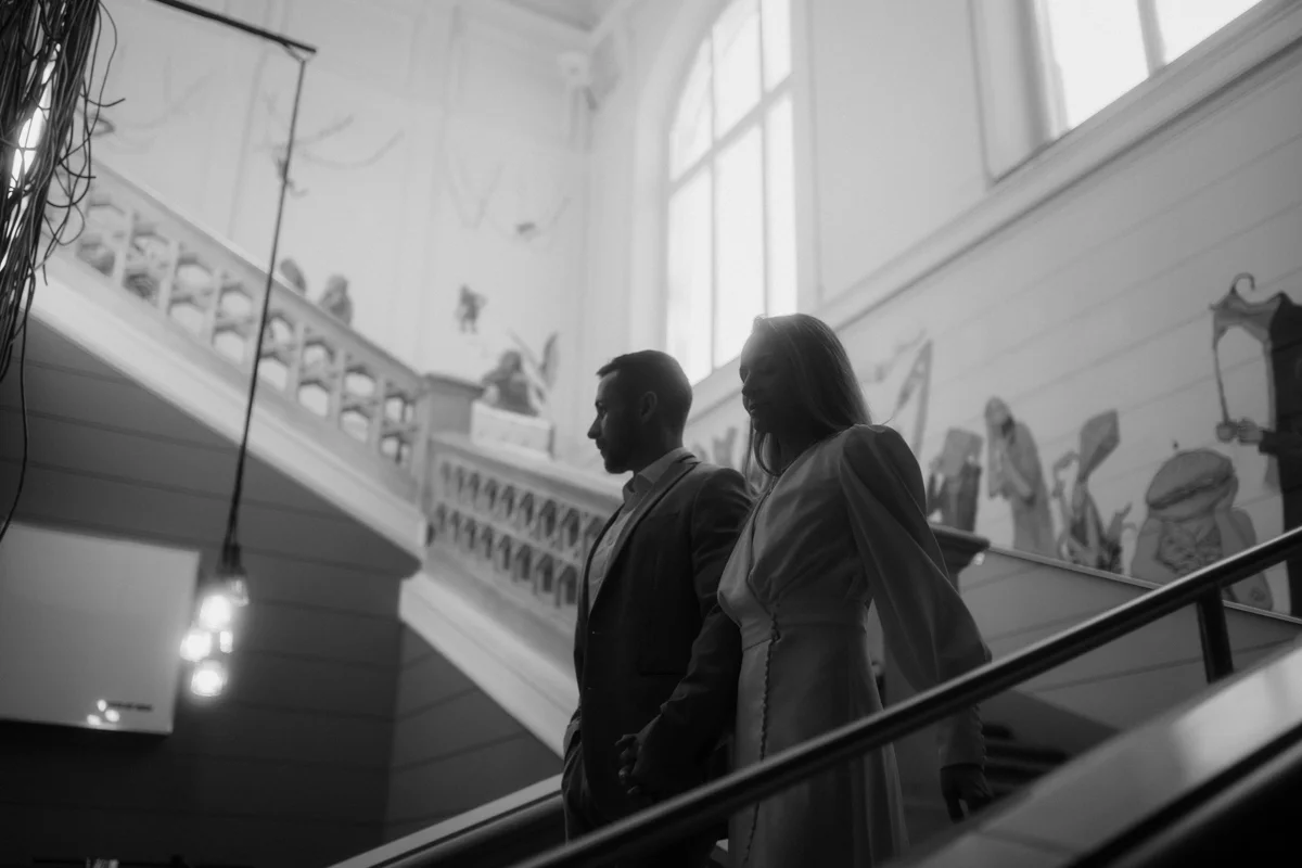 Brautpaar kommt die Treppe im Medienkulturhaus runter, fotografiert bei einem Hochzeit-Shooting in Wels, von Hochzeitsfotograf Kosia