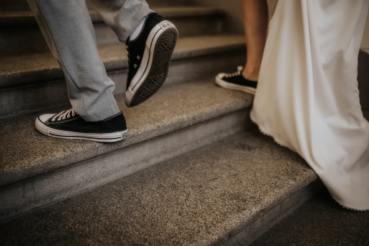 Detailfoto von einem Brautpaar das in Converse Chucks Schuhen eine Treppe hochläuft, fotografiert von Hochzeitsfotografin Kosia bei einem Hochzeit-Shooting in Wels