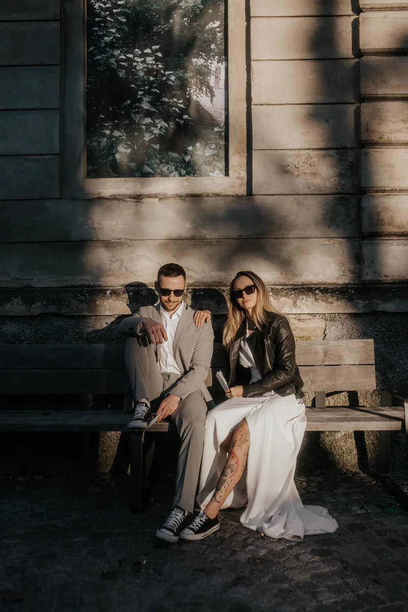 Brautpaar, das auf einer Bank sitzt und von der Sonne beleuchtet wird, fotografiert bei einem Hochzeit-Shooting in Wels