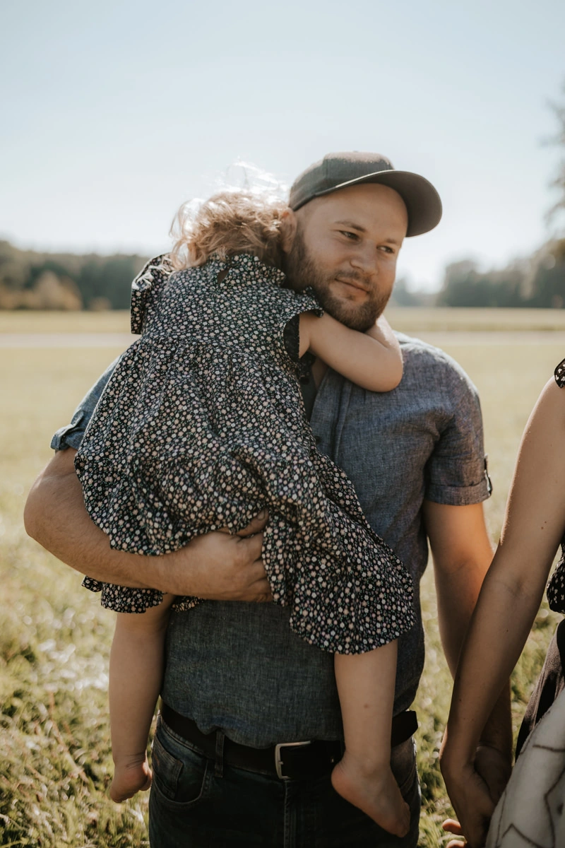 Ein Vater, der seine Tochter bei einem Newborn Shooting in Ried am Arm trägt, fotografiert von Fotograf Kosia