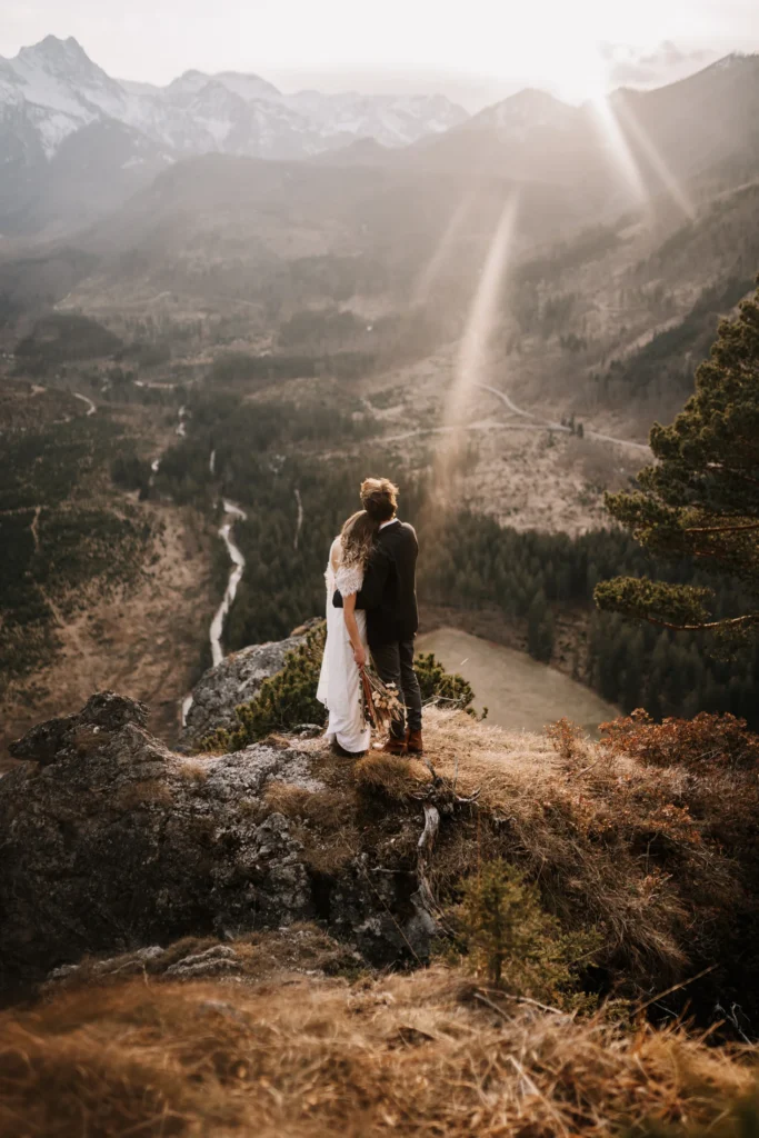 Frau mit Brautkleid und Mann mit Anzug auf einem Berg-Gipfel bei Sonnenuntergang im Herbst, fotografiert von Hochzeitsfotograf Nicole Salfinger aus Oberösterreich