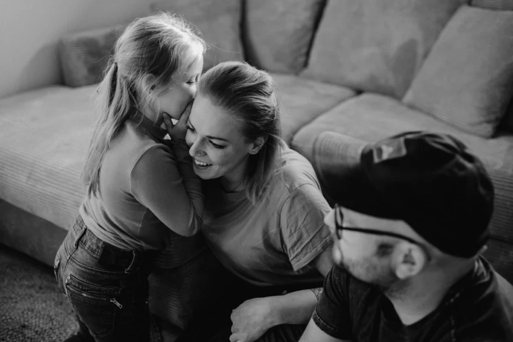 Schwarz-weiß Foto einer Familie die im Wohnzimmer Stille Post spielt, von Familienfotograf Kosia aus Oberösterreich