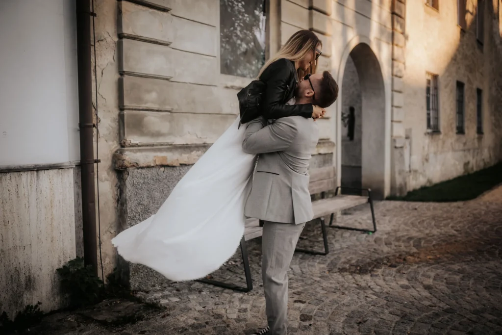 Elopement-Hochzeit in Wels Stadt in Österreich, fotografiert von Elopement Fotograf Kosia Photography. Der Bräutigam trägt seine Braut und wirbelt sie herum.